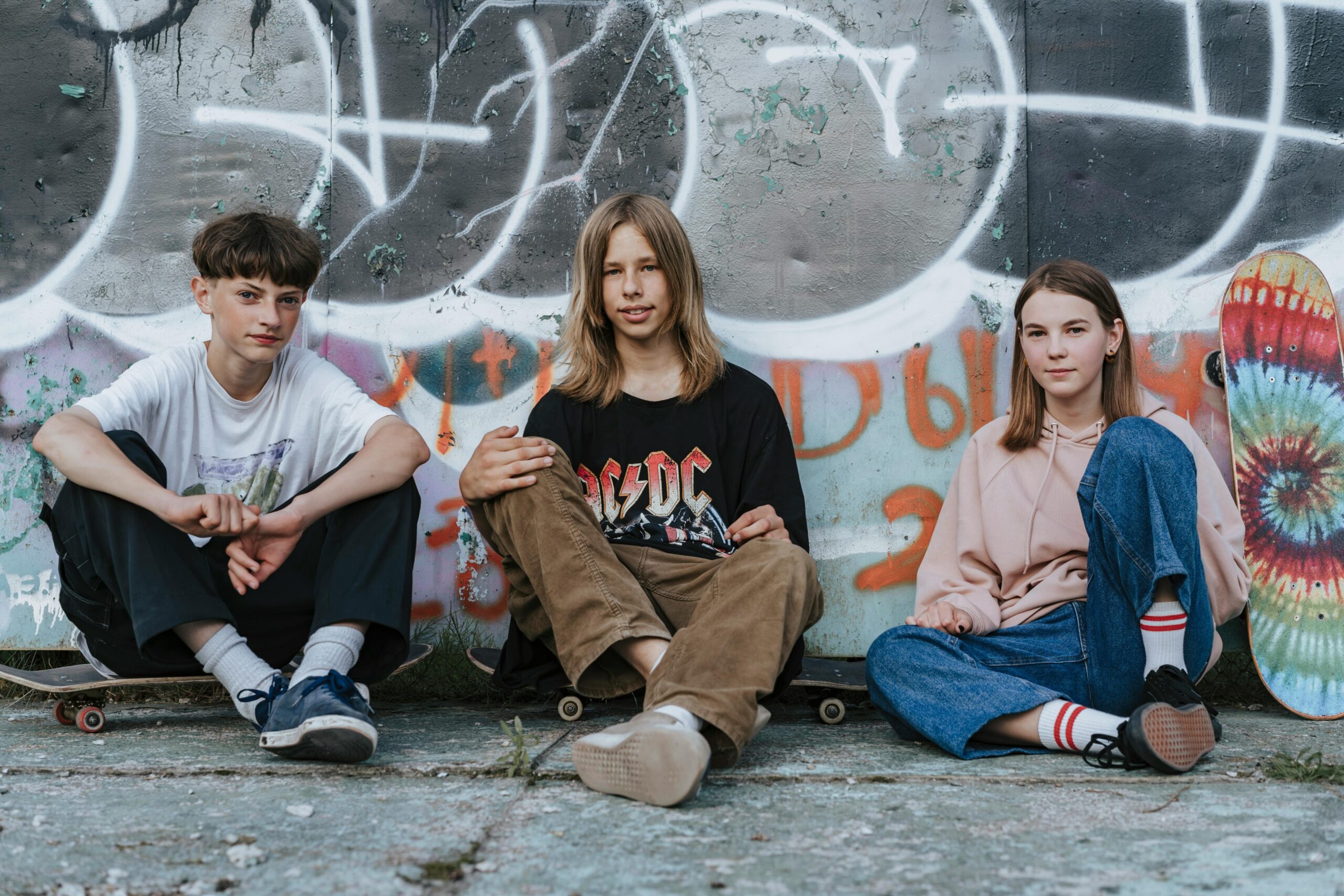 Teens sitting in front of a wall looking at camera